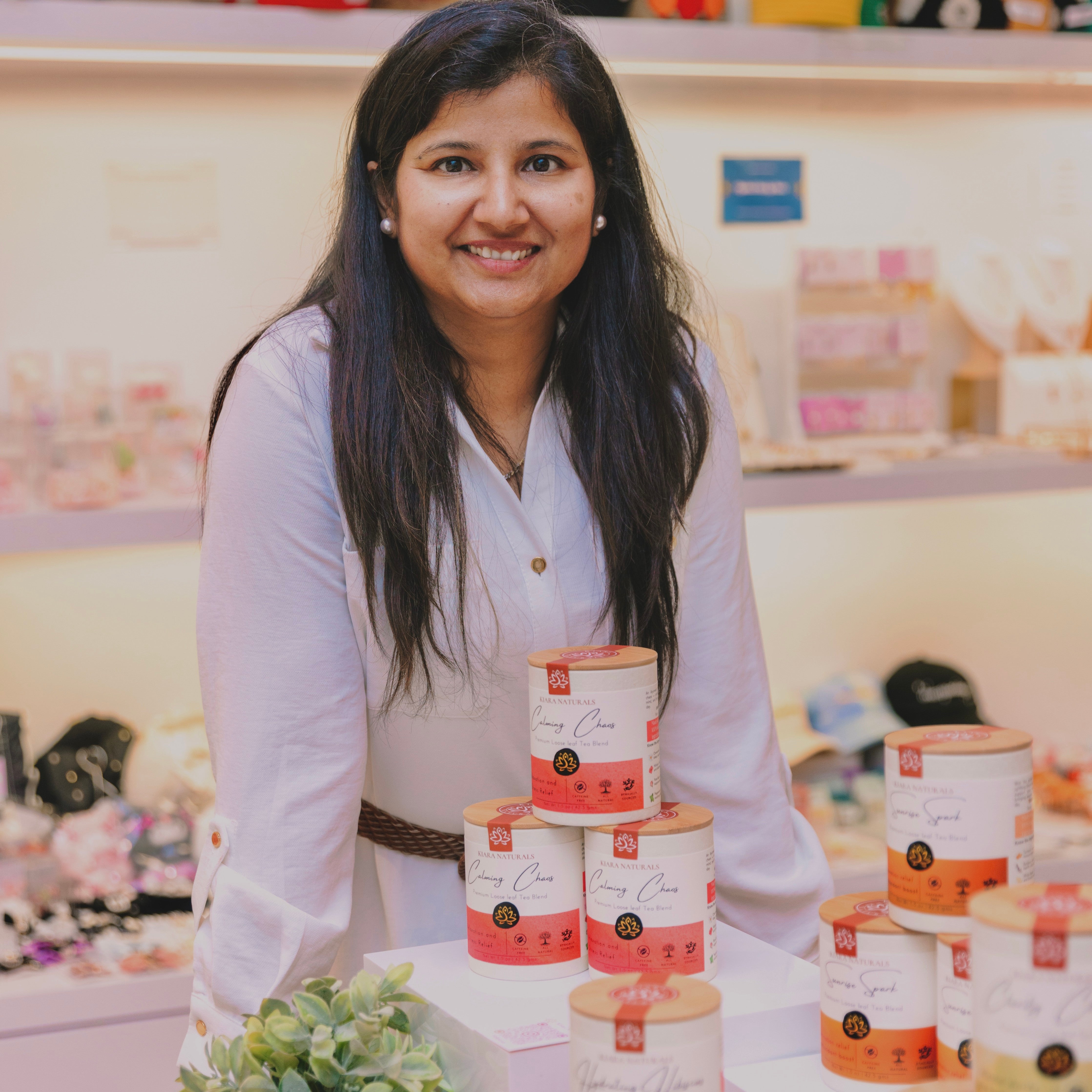 A smiling woman standing behind a display of tea canisters.
